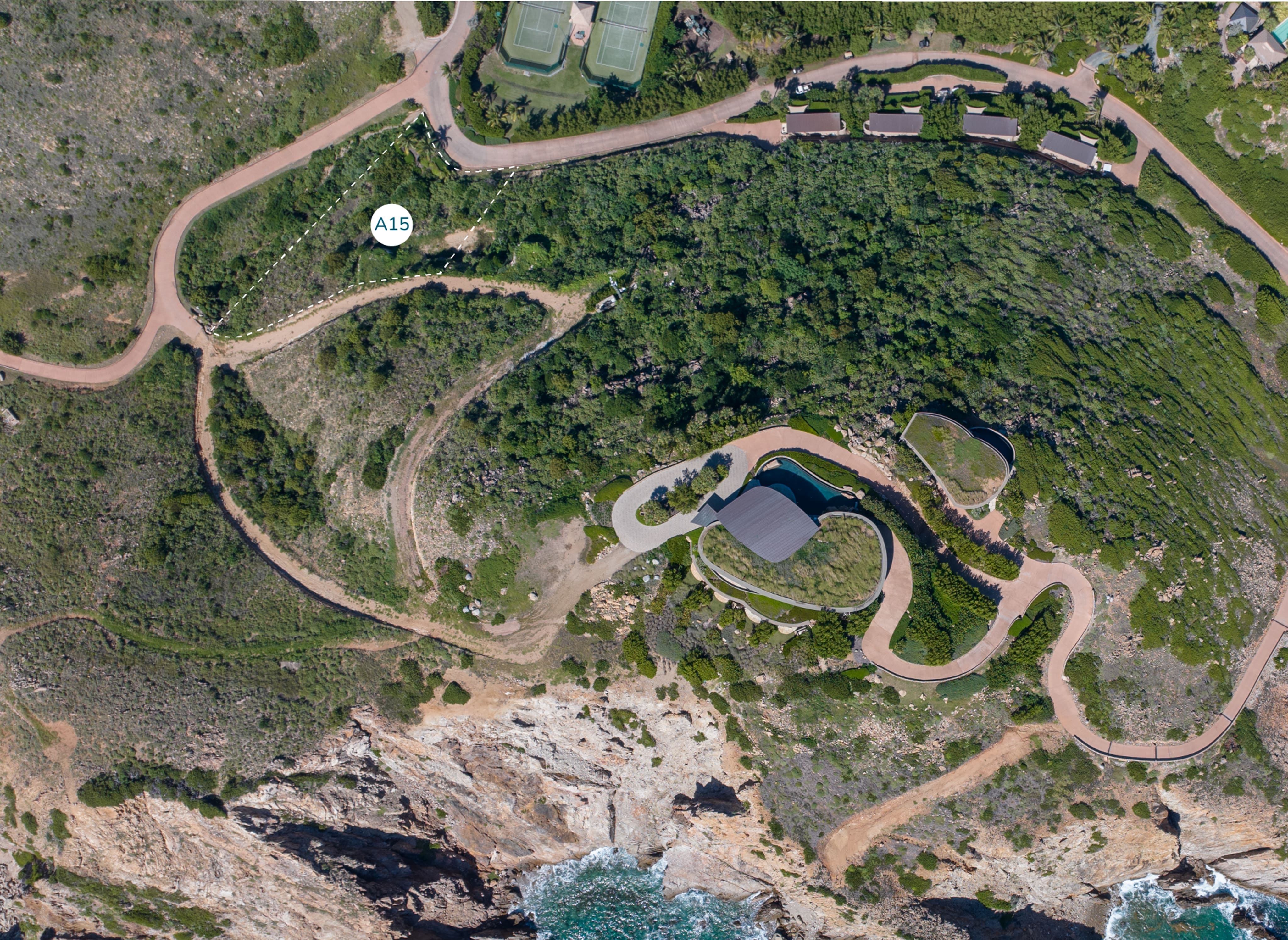 Aerial view of a coastal area with winding roads and a homesite near the cliff's edge. The landscape is green with some rocky sections, leading down to Atlantic Ridge shoreline where waves crash. Marked in the image is a spot labeled "A15" near a curving road.