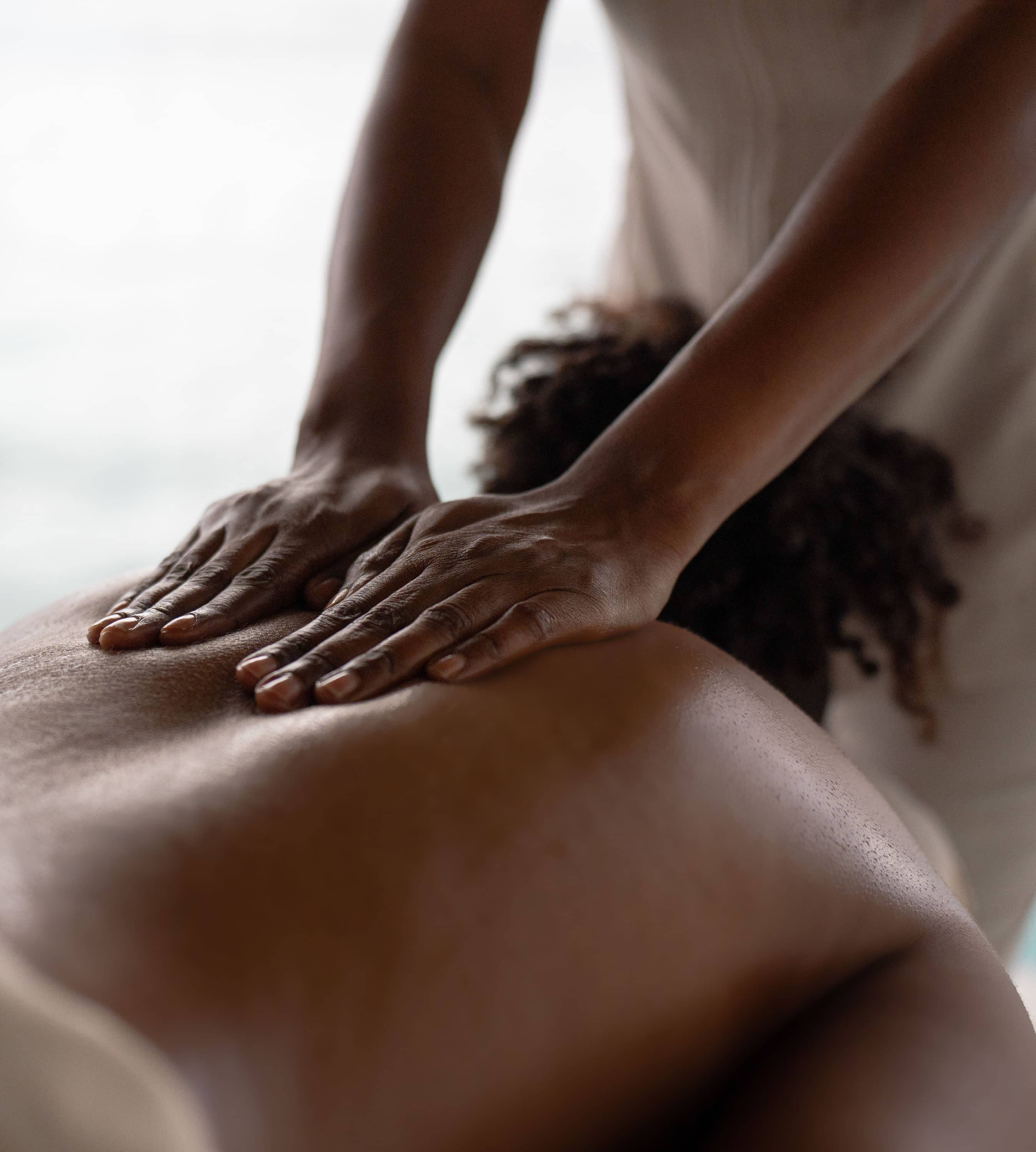 A close-up of a person receiving a back massage at the Oil Nut Bay spa, with the masseuse’s hands gently pressing on the client’s bare back. The softly blurred background adds to the calm and relaxing atmosphere.