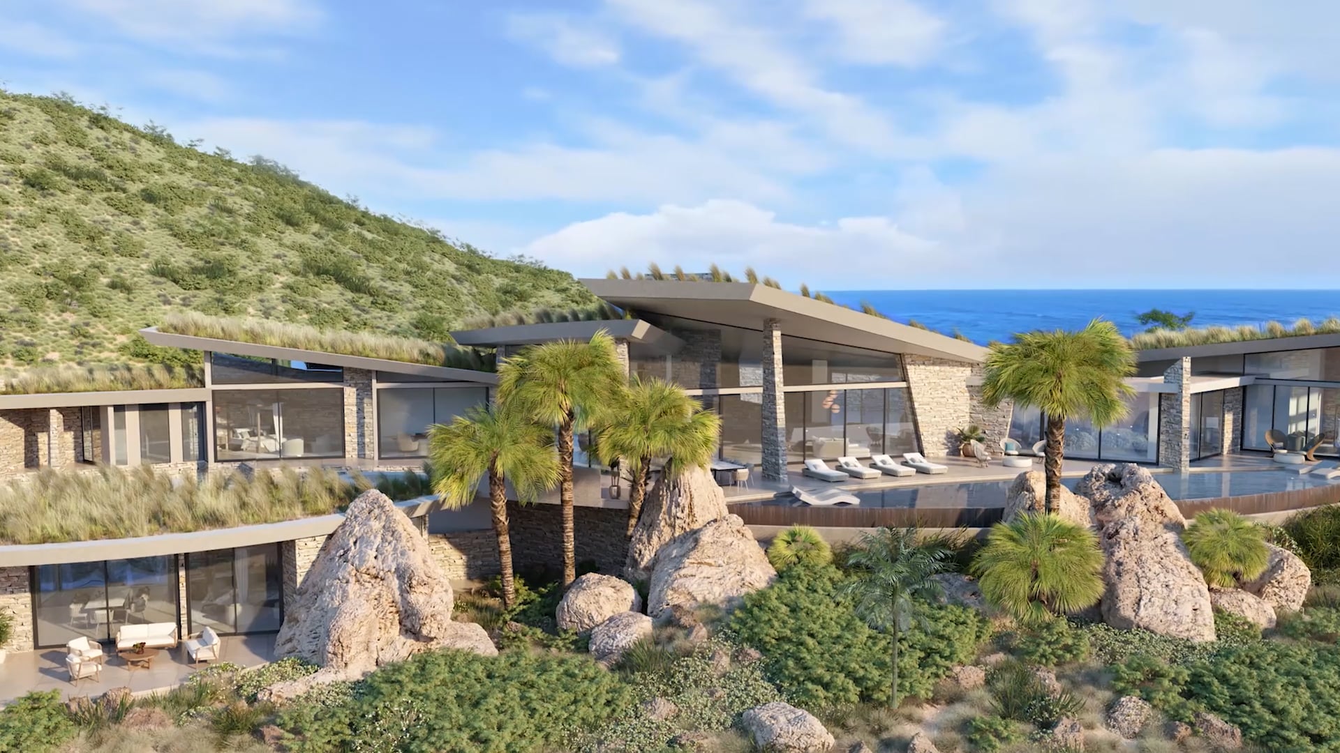 Modern luxury house nestled in a lush, green hillside with an ocean view. Known as Boulder Homesite, the house features large windows, multiple levels, and a spacious patio with sun loungers. Palm trees and large rocks are scattered around the property, blending seamlessly with the natural landscape for added inspiration.