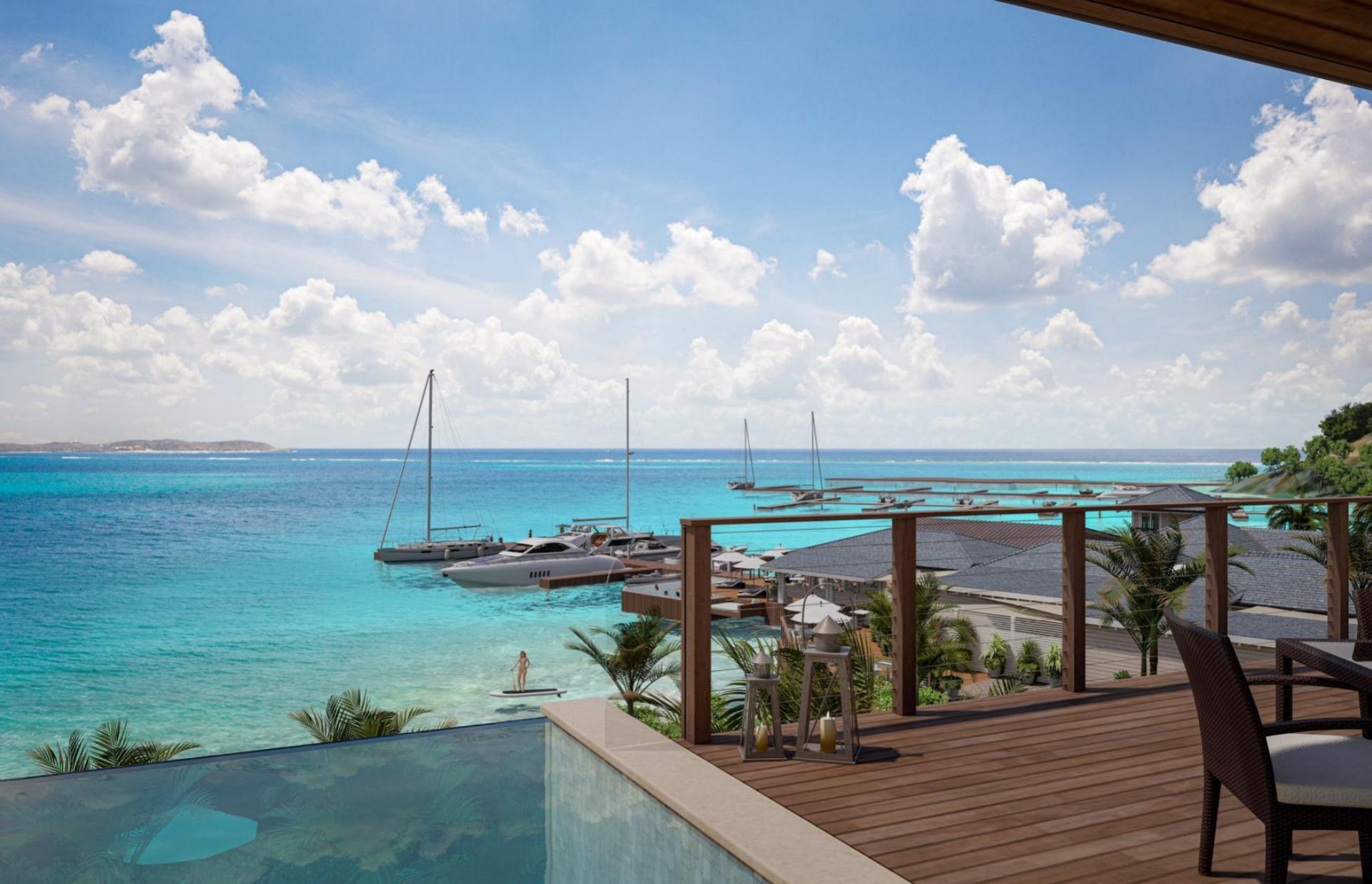 View from a wooden deck overlooking a turquoise sea with sailboats and yachts docked at a marina. The scene includes a clear sky dotted with fluffy clouds, palm trees below, and a luxurious outdoor lounge area on the deck.