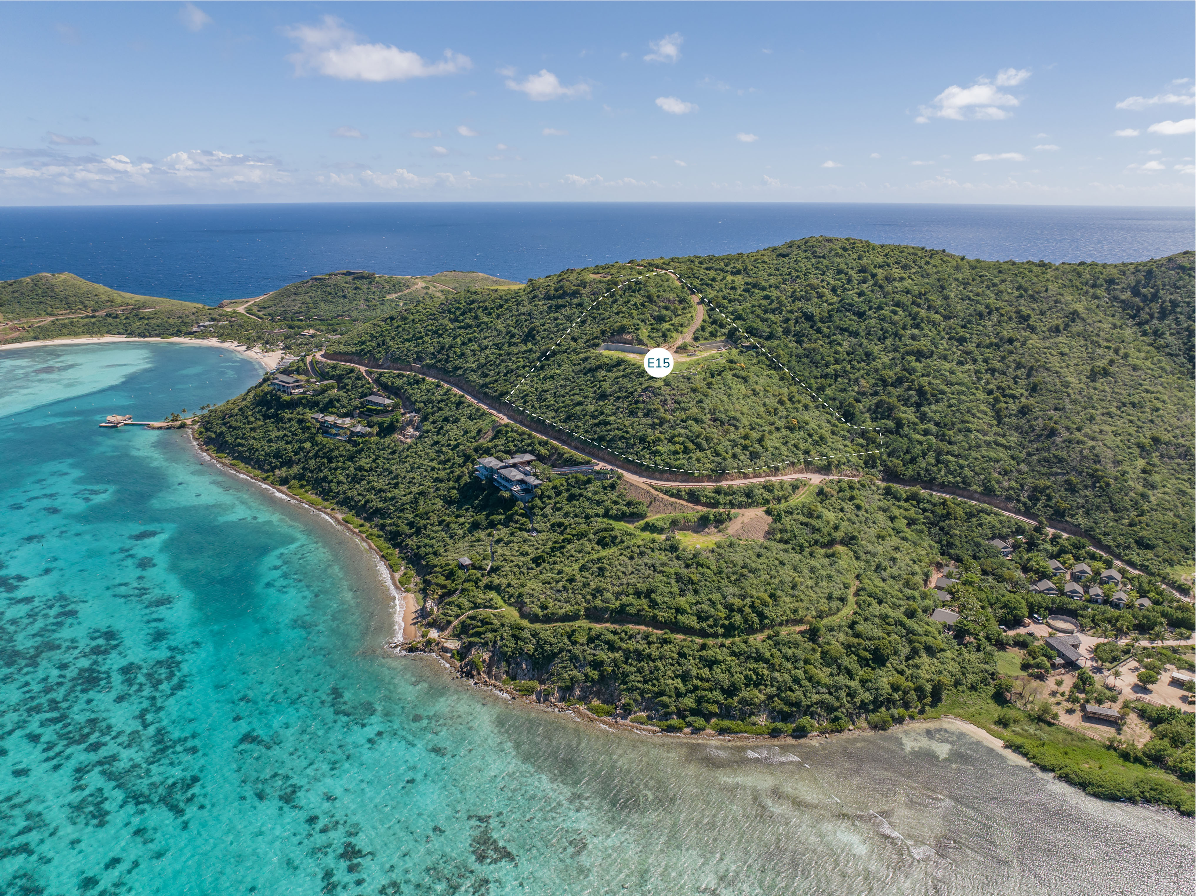 Aerial view of a lush green hillside overlooking a turquoise ocean bay. A road curves through the foliage, with an Estate Homesite nestled in the scenery. A white circle with "E16" is marked on the hill. The sky is clear with a few clouds.