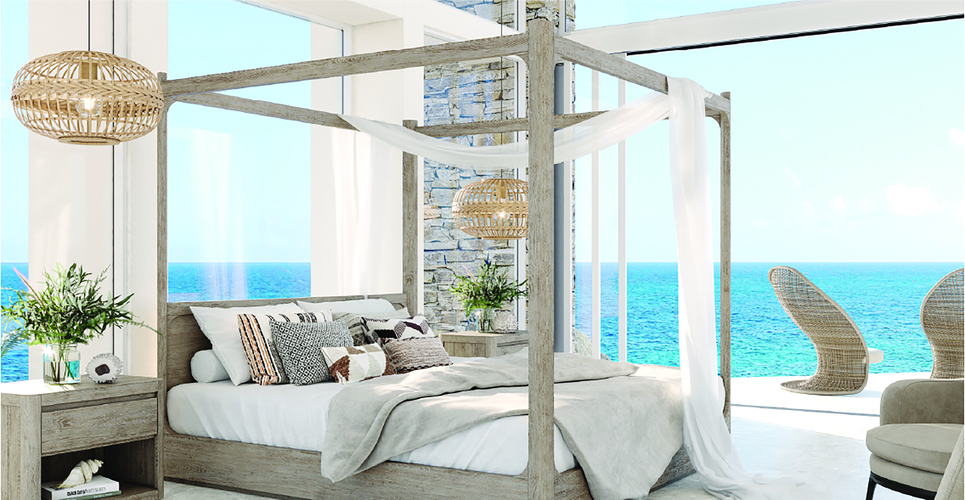 A bright, airy Boulder Homesite bedroom overlooking the ocean features a four-poster bed with draped white fabric and a mix of pillows. Two woven pendant lights hang above a side table with plants, and large windows display the sea and sky in the background.