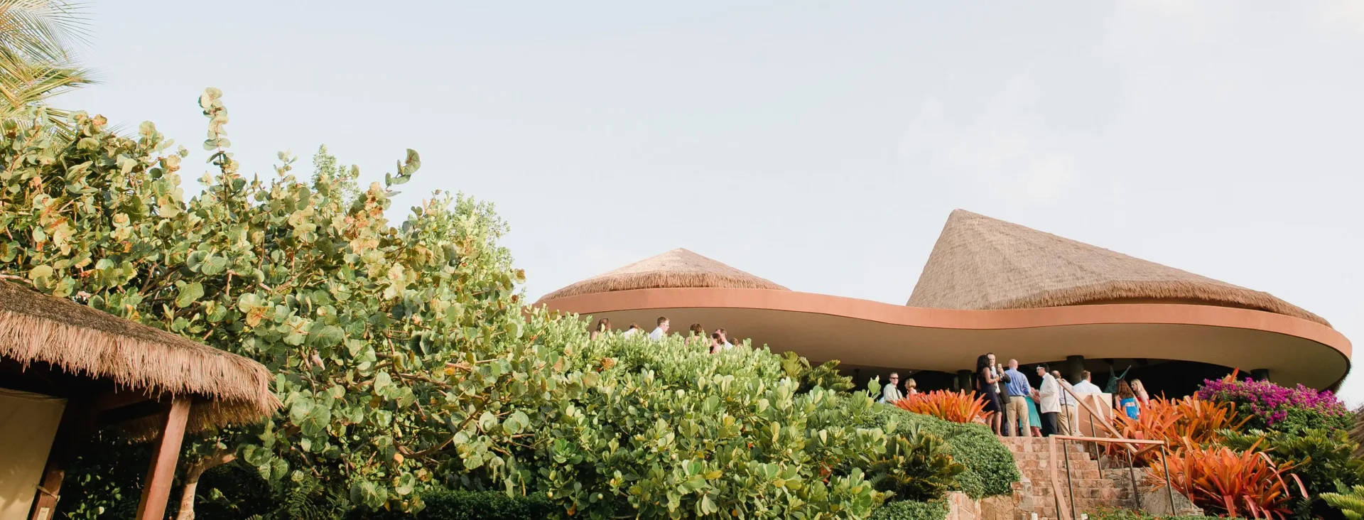 Discerning guests gathering at the Pavilion for a private event, showcasing the grounded architecture, thatched roofing, and lush tropical landscaping that define the secluded luxury of Oil Nut Bay.