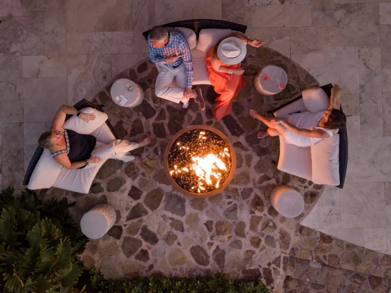 An intimate and exclusive evening gathering around a glowing stone fire pit, where guests relax in comfortable outdoor seating under the starlit Caribbean sky.