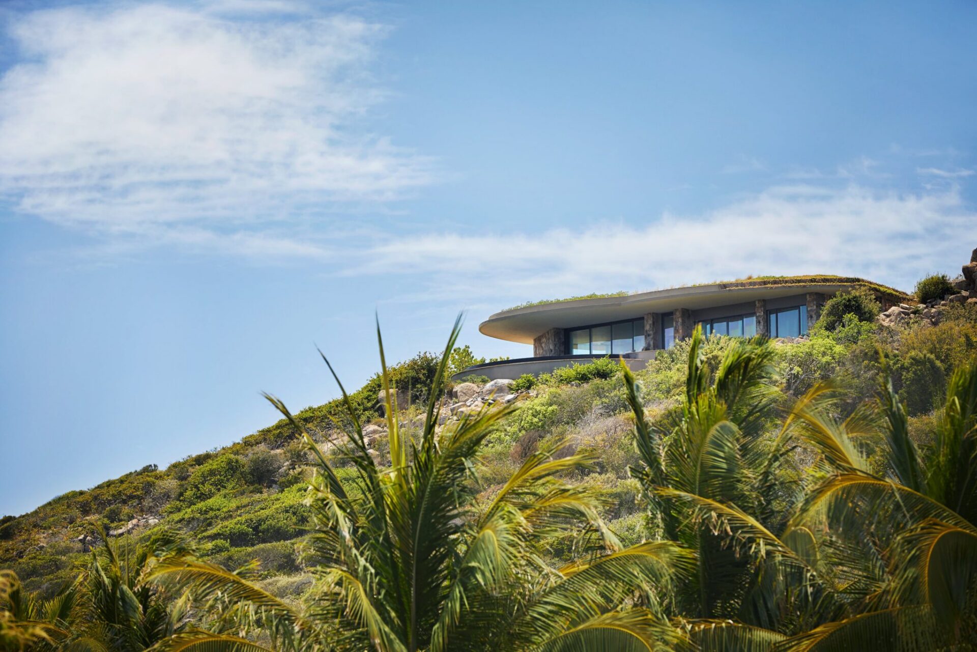 A low-density luxury home at Oil Nut Bay architecturally cut into the dramatic hillsides and ridges of Virgin Gorda, featuring a green rooftop that naturally blends into the surrounding tropical flora.