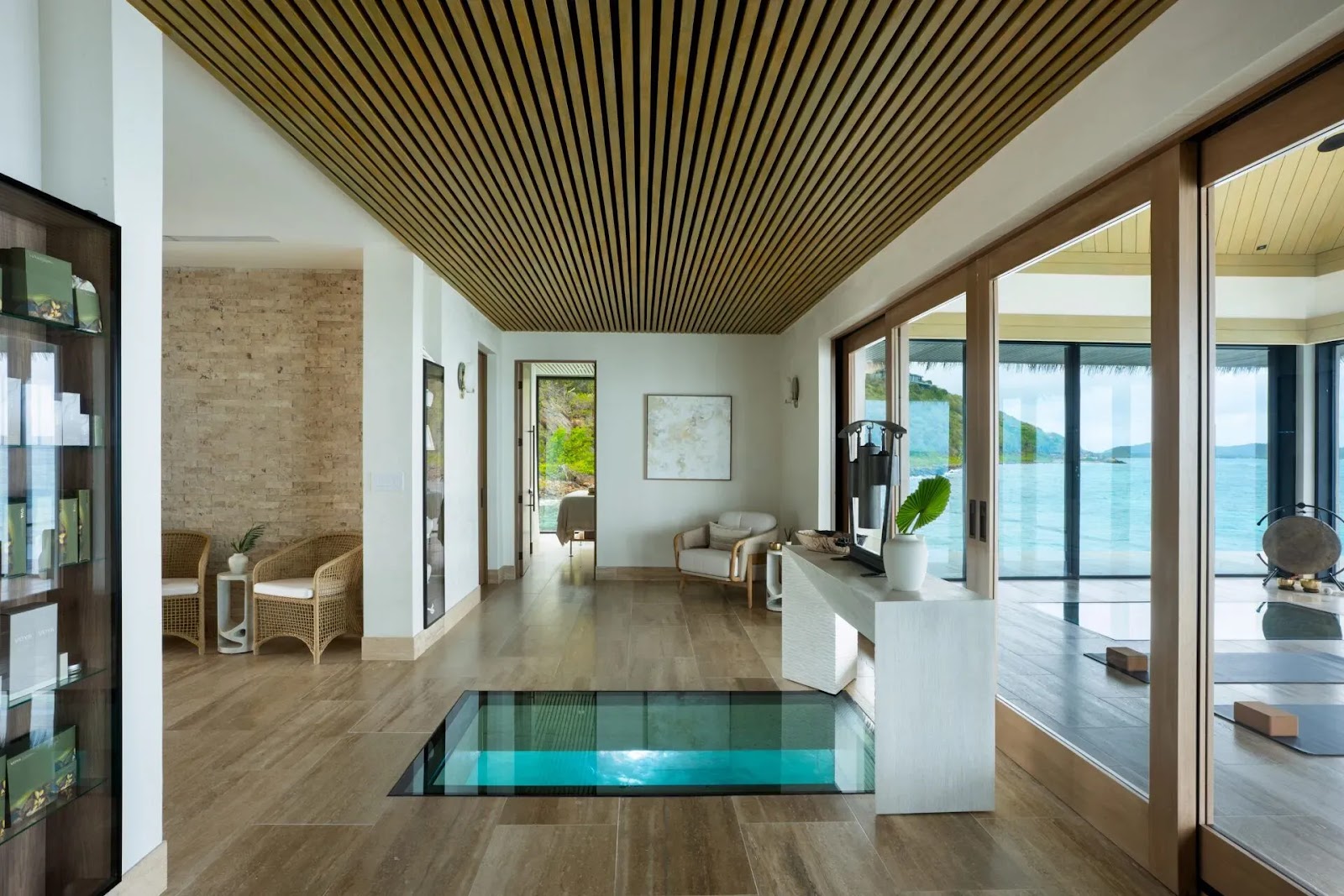 Glass floor panel revealing turquoise water in the light-filled lobby of Sundara Spa + Studio at Oil Nut Bay.