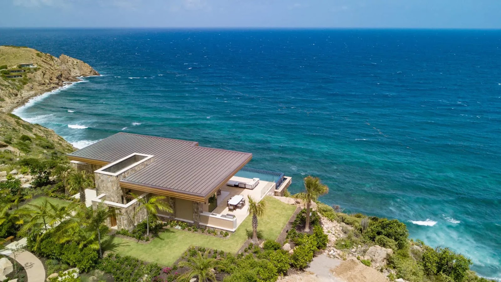 Aerial view of a cliffside villa at Oil Nut Bay perched over deep blue Caribbean waters in Virgin Gorda.