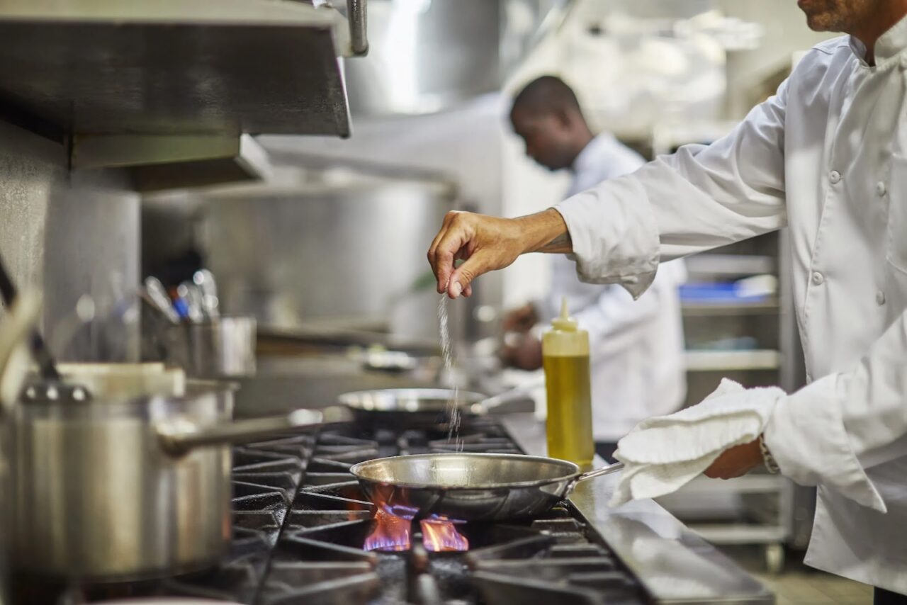 A chef adding finishing touches to a dish on the stove in an Oil Nut Bay kitchen.