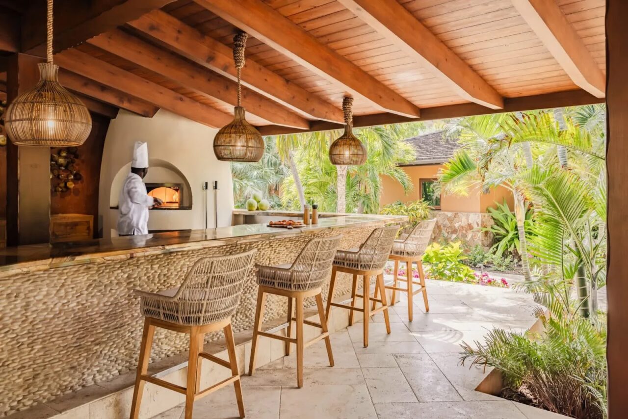 A chef preparing pizza in a wood-fired oven behind an open-air pavilion bar at Oil Nut Bay.