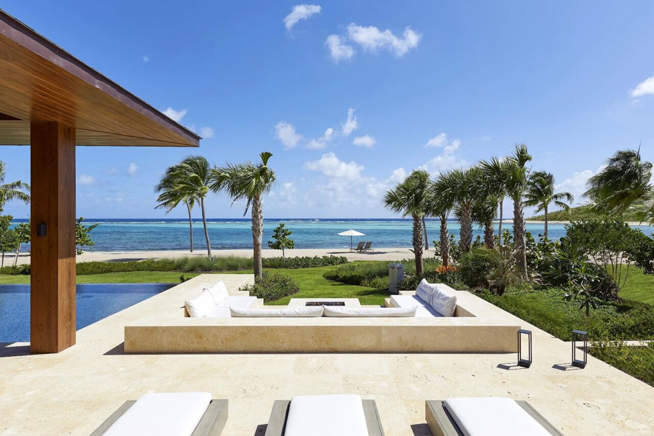 Oil Nut Bay beachfront villa featuring a sunken patio lounge, private pool, palm trees, and turquoise bay views.