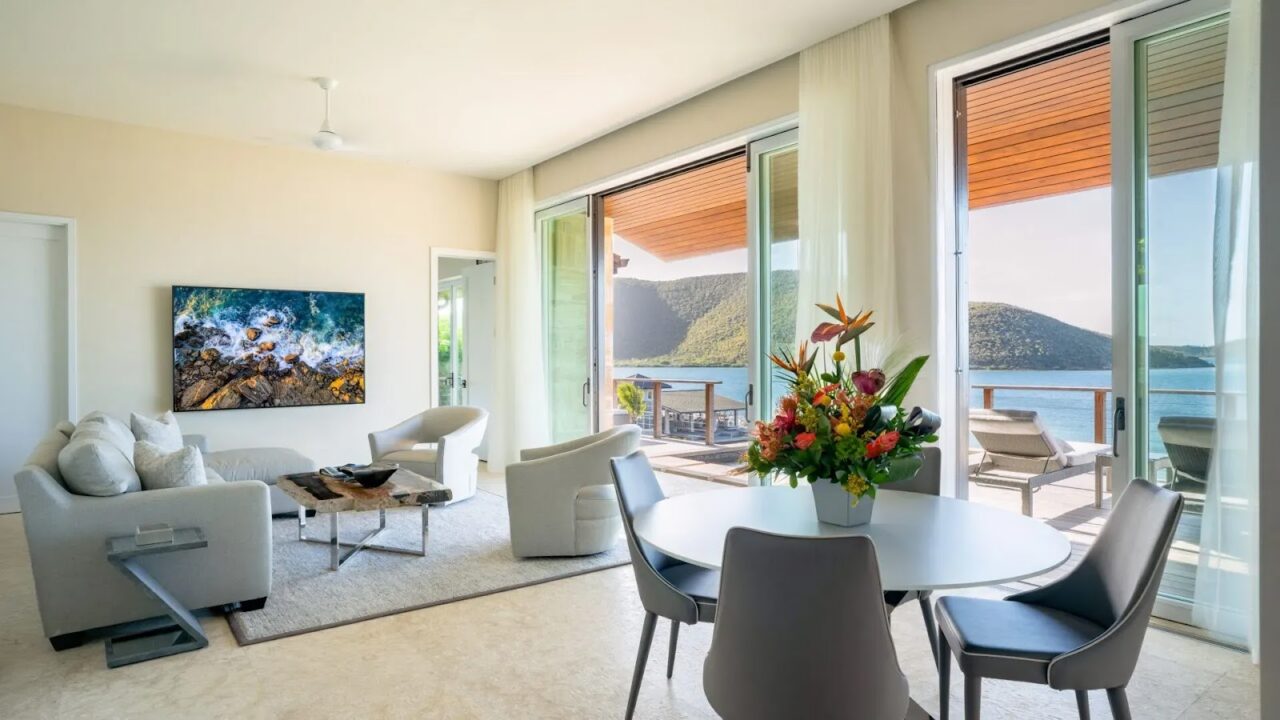 Luxury villa interior at Oil Nut Bay with open glass doors, dining table, and scenic Virgin Gorda ocean views.