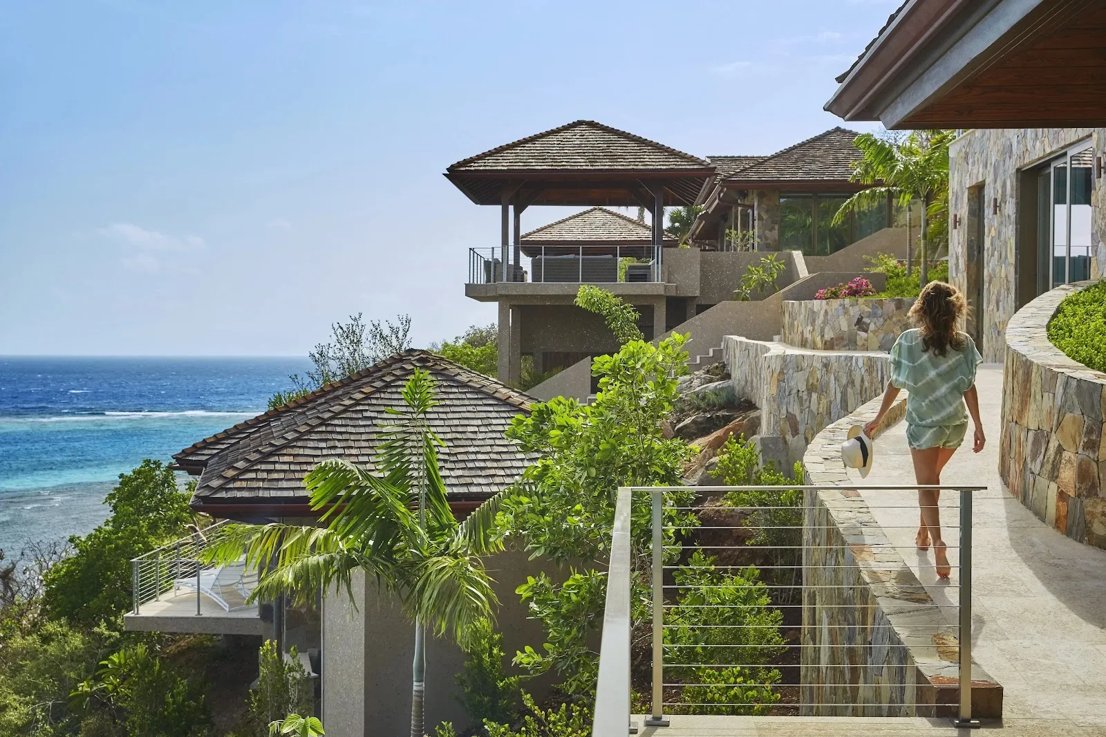 A guest walking along the stone terrace of a private cliffside villa with Caribbean Sea views.