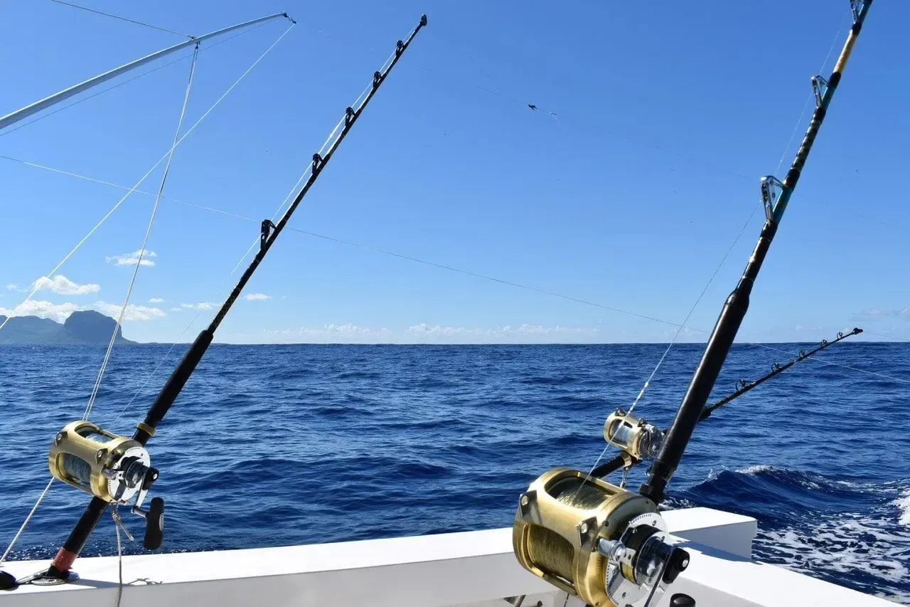 Two deep-sea fishing rods mounted on a private boat charter sailing clear ocean waters